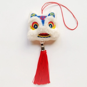 Vue détaillée de la tête de lion en peluche blanche avec de longs glands en soie rouge