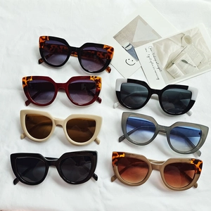 Chic cat-eye sunglasses collection in various colors displayed on a white fabric background