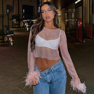 Détail du crop top en maille rose avec strass brillants et plumes aux poignets