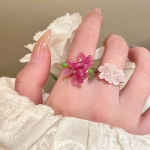 Close-up of resin flower beaded rings in rose pink and milky white on fingers