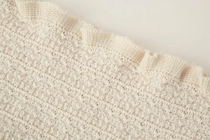 Vue macro détaillée du tissu tricoté crème avec des textures de l'ourlet ondulé