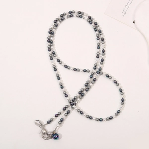 Detail of beaded crossbody strap with dark iridescent beads and white faux pearls