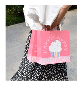Close-up of pink gift bag with cartoon cupcake illustration and pink handle straps