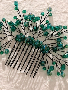 Macro view of handmade hair comb with emerald crystals and black woven wire leaves