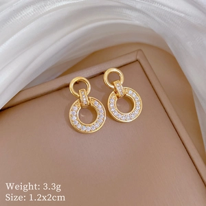 Close-up of gold geometric earrings with pavé zircons showing 1.2x2cm size and 3.3g weight