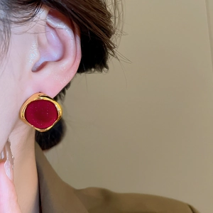 Close-up of a vintage-style gold geometric earring with red flocking on a model's ear