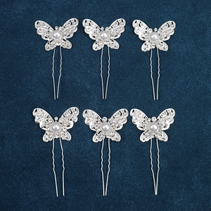 Detail of six silver butterfly hair pins with crystals and pearls on blue fabric