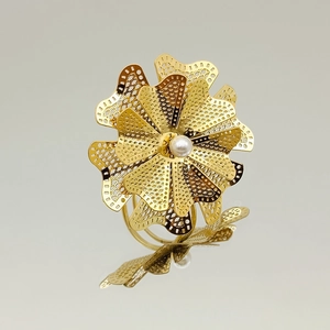 Detailed macro view of layered hollow golden flower ring with a center pearl and mirror reflection