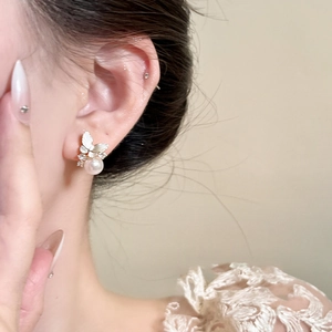 Elegant butterfly stud earrings with sparkling crystals and a white round pearl drop on model