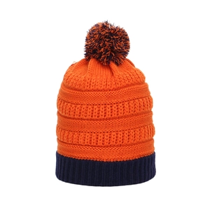 Détail d'un bonnet en tricot bicolore orange et bleu marine avec pompon et maille épaisse