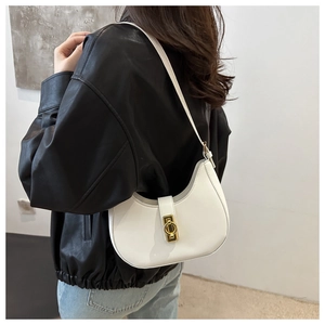 Chic white crescent shoulder bag with gold hardware shown on a model in casual wear