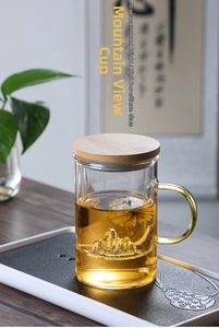Detailed view of heat-resistant glass tea cup with wood lid and mountain base design