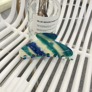 Detail of large acetate hair claw clip with colorful blue, green and yellow striped texture