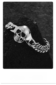 Macro shot of punk skull charm and heavy metal chain on black rock background