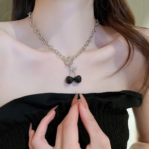 Close-up of black cherry pendant on silver OT buckle necklace worn by a fashion model