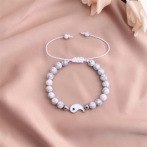 Dettaglio del bracciale con perline di marmo bianco e ciondolo Yin Yang su seta rosa