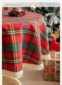 Detail of red and green plaid Christmas tablecloth with gold threads and beige tassels