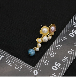 Detailed view of pearl drop earrings with size reference on professional black background