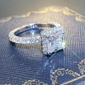 Macro detail of a princess cut halo diamond ring showcased on a blue velvet jewelry box