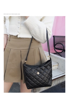 Detail of black quilted shoulder bag with golden flower hardware and diamond pattern