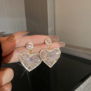 Close-up of heart-shaped crystal earrings with pink rhinestone and sparkling accents