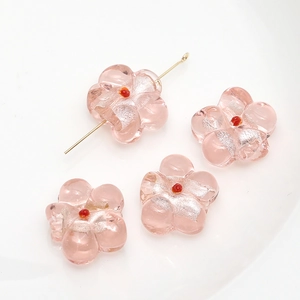 Macro view of pink glass flower beads with silver foil and red center for DIY jewelry