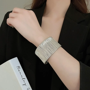 Macro detail of silver textured metal bangle with vertical lines on female wrist