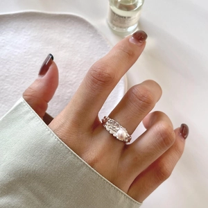 Detail of irregular silver ring with white pearl on hand against aesthetic backdrop