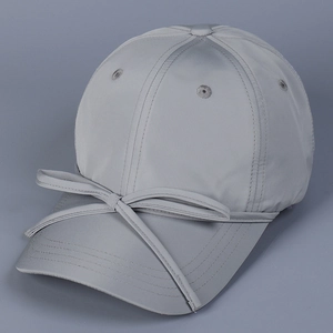 Detail of light grey satin baseball cap featuring a delicate bow tie on the brim