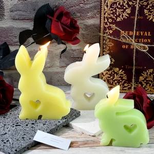 Three Easter bunny candles in yellow, white, and green with hollow heart-shaped designs