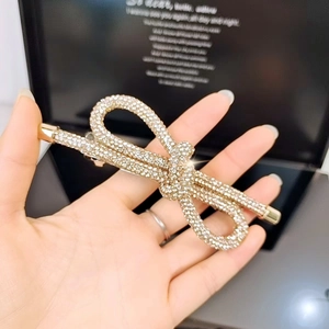Dettaglio del fermaglio per capelli a fiocco dorato con strass su scatola regalo di lusso