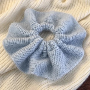 Detailed close-up showing soft blue knitted wool texture and ruffled edge hair scrunchie