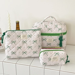 Three-piece quilted makeup bag set featuring green bow and polka dot patterns on cream fabric