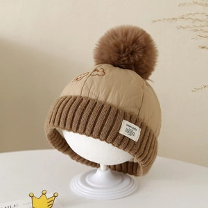 Détail du bonnet d'hiver kaki avec pompon en fausse fourrure marron et étiquette tissée