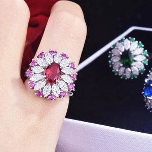 Close-up of a floral cocktail ring with a red oval gem and sparkling petal diamonds
