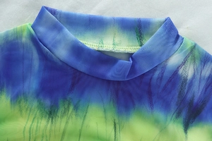 Détail du haut en résille tie-dye multicolore avec col montant et tissu mesh transparent