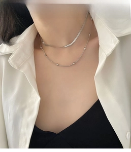 Detail of silver double-layered necklace featuring flat snake chain and bead accents
