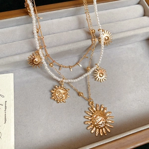 Detail of triple-layer gold sun pendant necklace with pearls and vintage sun medallions