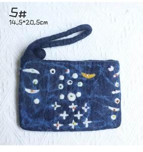 Close-up of handmade navy wool felt bag with colorful moon embroidery and bead charms