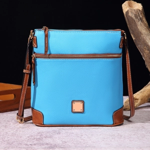 Detailed macro view of pebble grain leather texture and metal zipper on blue crossbody bag