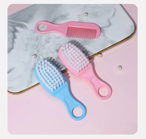 Detailed view of pink and blue baby grooming hairbrush set on a marble tray