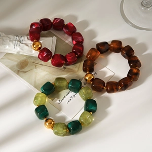 Detail of beaded resin bracelets with marble texture and large gold metal bead