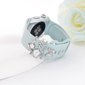 Detail of silver decorative charms with white rhinestones on a light blue silicone strap