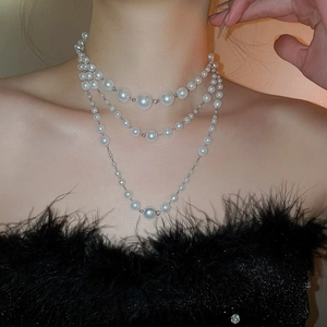 Detail of elegant triple-layered pearl necklace with gradient white pearls on neck