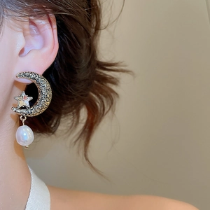 Detailed shot of crescent moon earring with star crystal and hanging white pearl drop
