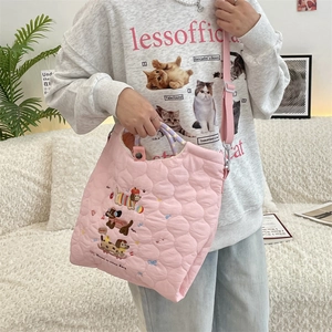 Pink quilted shoulder bag with dog embroidery shown being worn by a model in a cozy room