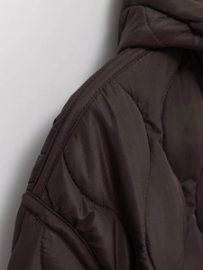 Macro detail of dark brown quilted puffer jacket shoulder with precise stitching