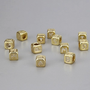 Makroaufnahme goldener Buchstabenperlen mit Strasssteinen für DIY-Schmuckherstellung