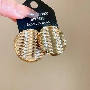 Golden ripple geometric round acrylic earrings on card with textured surface