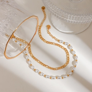 Detail of double-layer stainless steel anklet with gold chain and white pearl beads